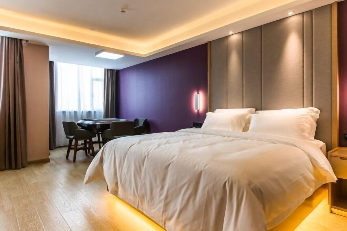 Quarto de hotel moderno com uma cama grande, uma mesa e uma cadeira.