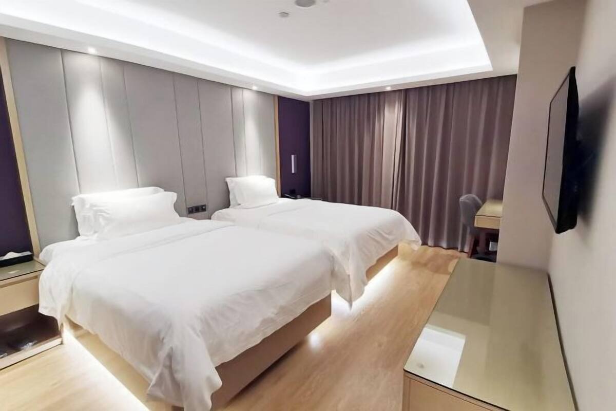 A modern hotel room with a large bed, a desk, and a TV.