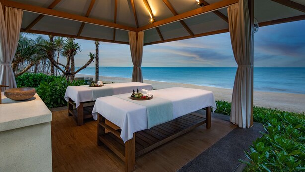 A beachside spa area with two massage tables under a wooden canopy, overlooking the ocean. - Radisson Resort Phan Thiet (Tien Thanh)