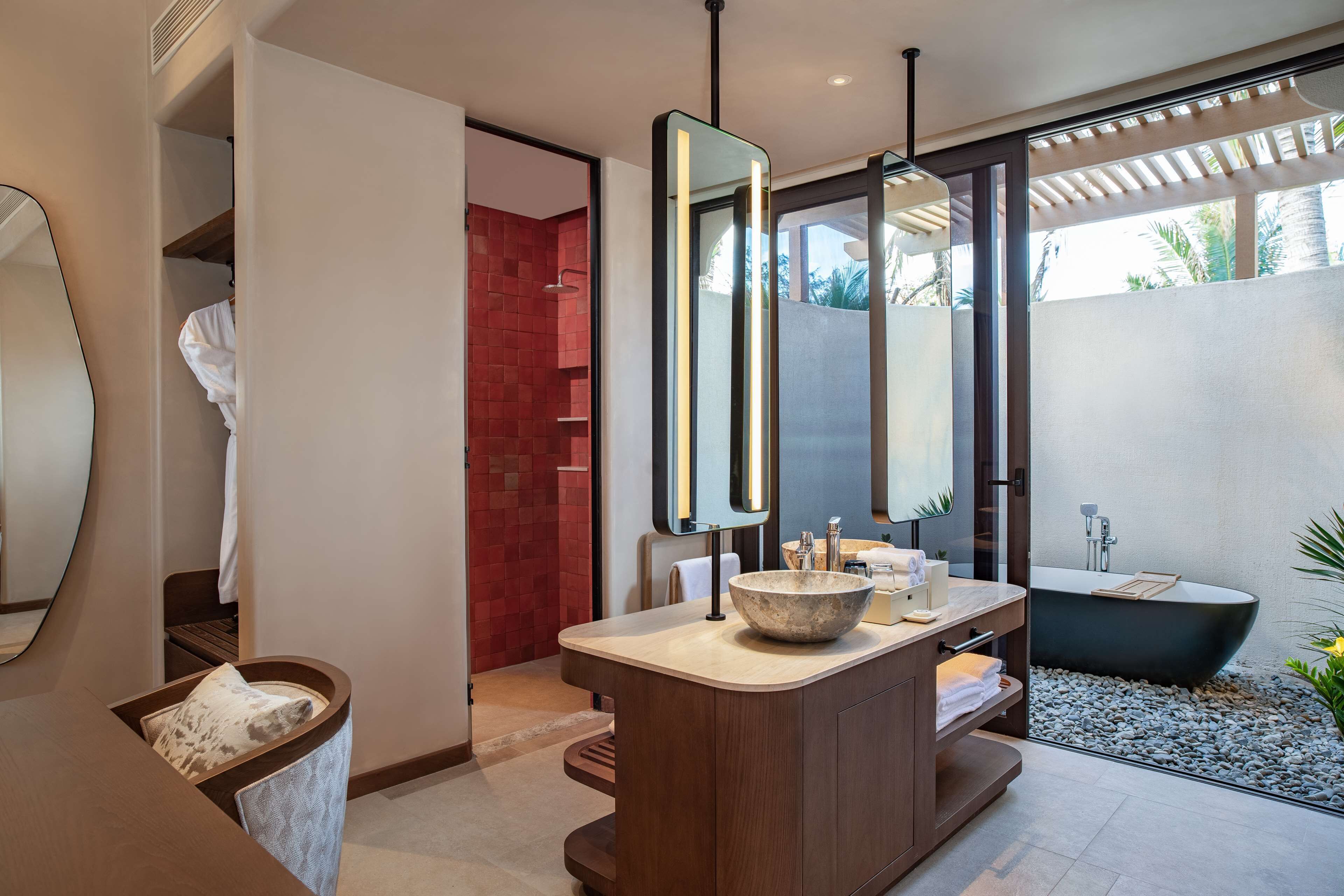 Un baño moderno con una bañera independiente, un espejo grande y un tocador con lavabo.