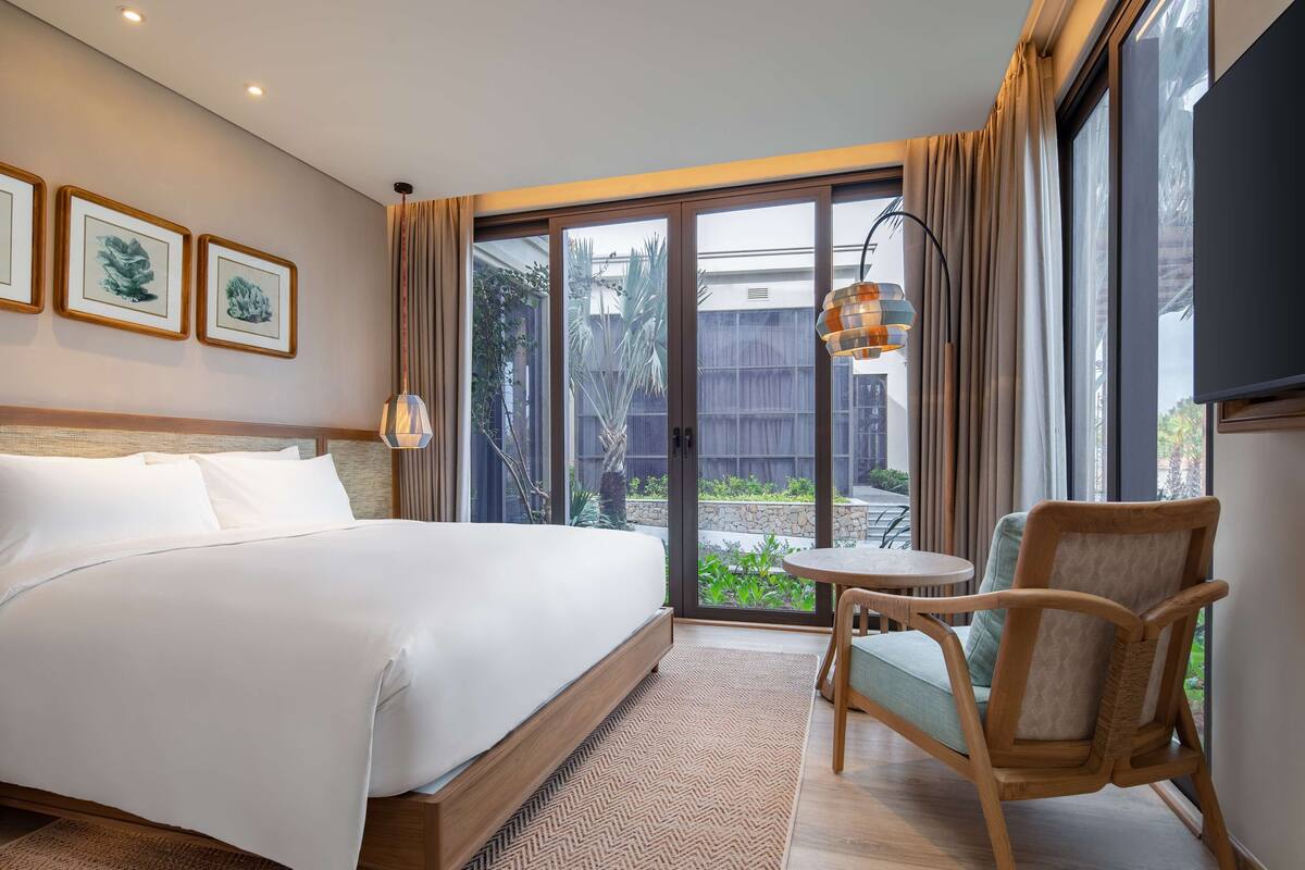 Una habitación de hotel con cama, una silla, una mesa y vistas al exterior.