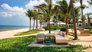 A beachside lounge with outdoor seating, palm trees, and a view of the ocean. - Radisson Resort Phan Thiet (Tien Thanh)