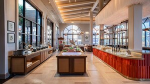 A spacious hotel lobby with a central reception desk, large windows, and a high ceiling with exposed beams. - Radisson Resort Phan Thiet (Tien Thanh)