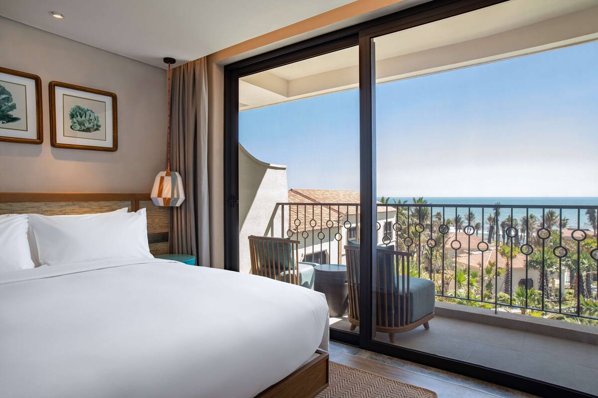 Habitación de hotel con una cama grande, vistas al balcón y dos cuadros en la pared.
