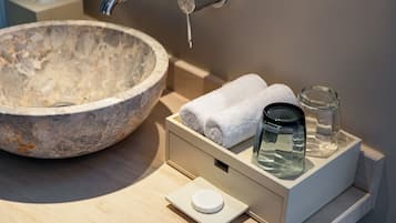 A bathroom with a stone sink, a towel warmer, and a glass jar.