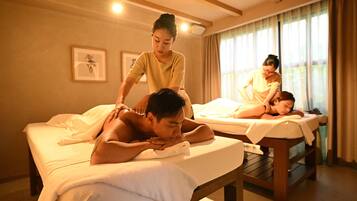 A massage therapy room with two massage tables, a wooden bench, and a framed picture on the wall.