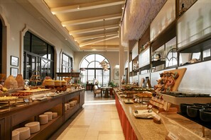 A buffet area with various food stations, a seating area, and a large arched window. - Radisson Resort Phan Thiet (Phan Thiet)