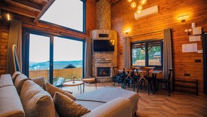 A cozy cabin interior with a fireplace, wooden walls, a sofa, and a dining area. - Woodlodge Country Sapanca (Sapanca)