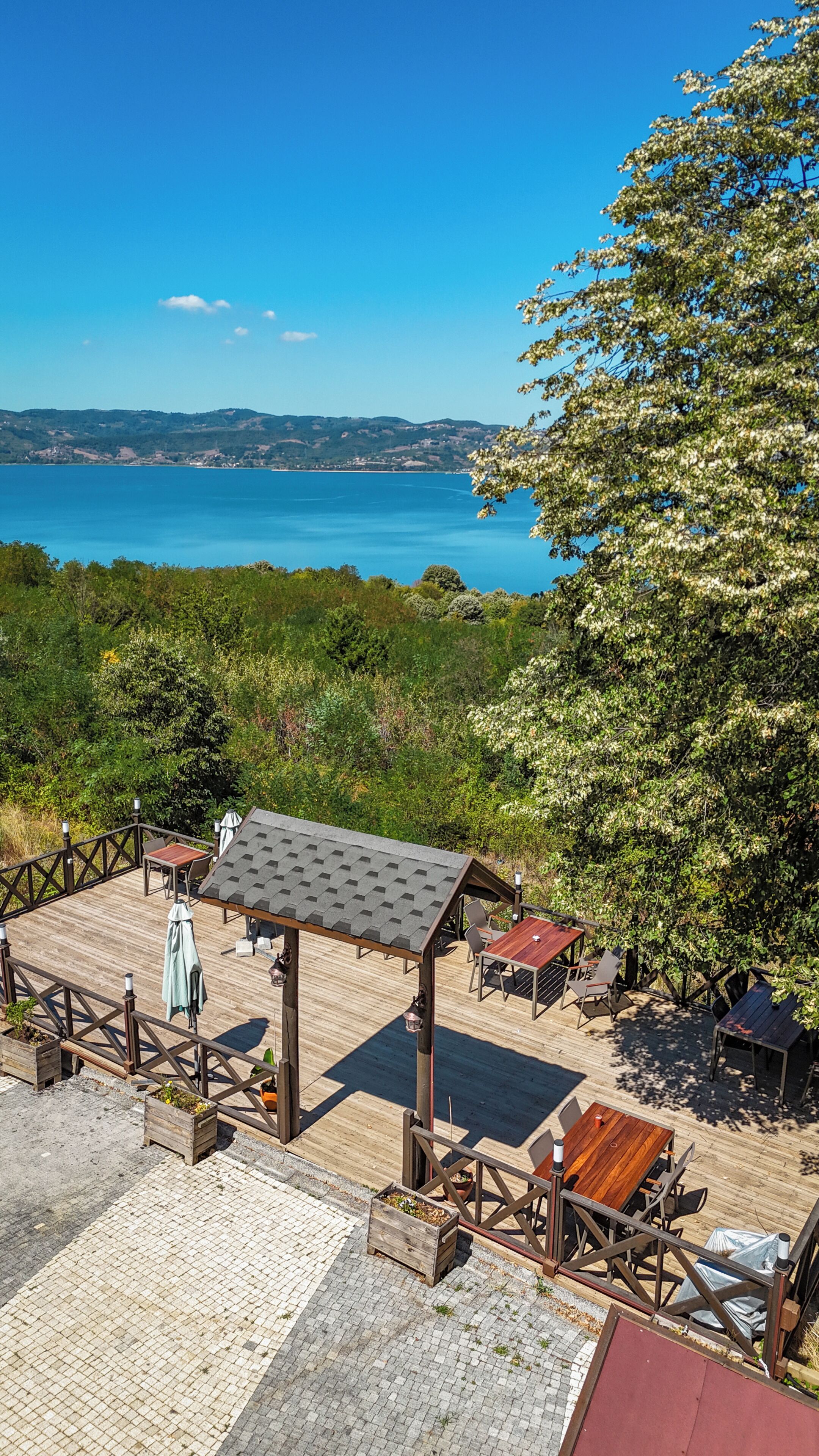 Une terrasse en bois avec des meubles d’extérieur, une pergola et une vue sur un lac.