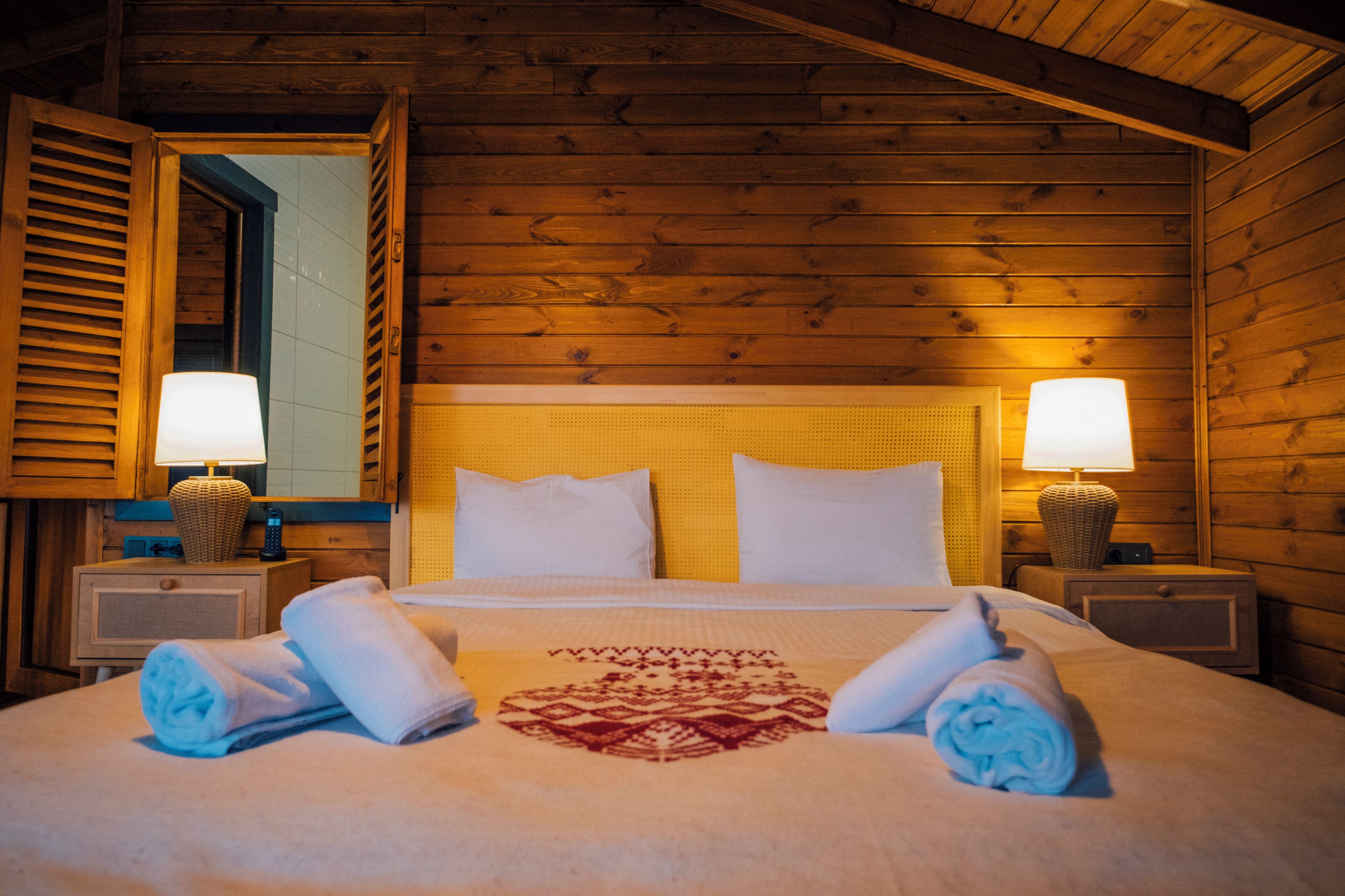 Una habitación de madera con una cama, dos mesitas de noche y dos lámparas.