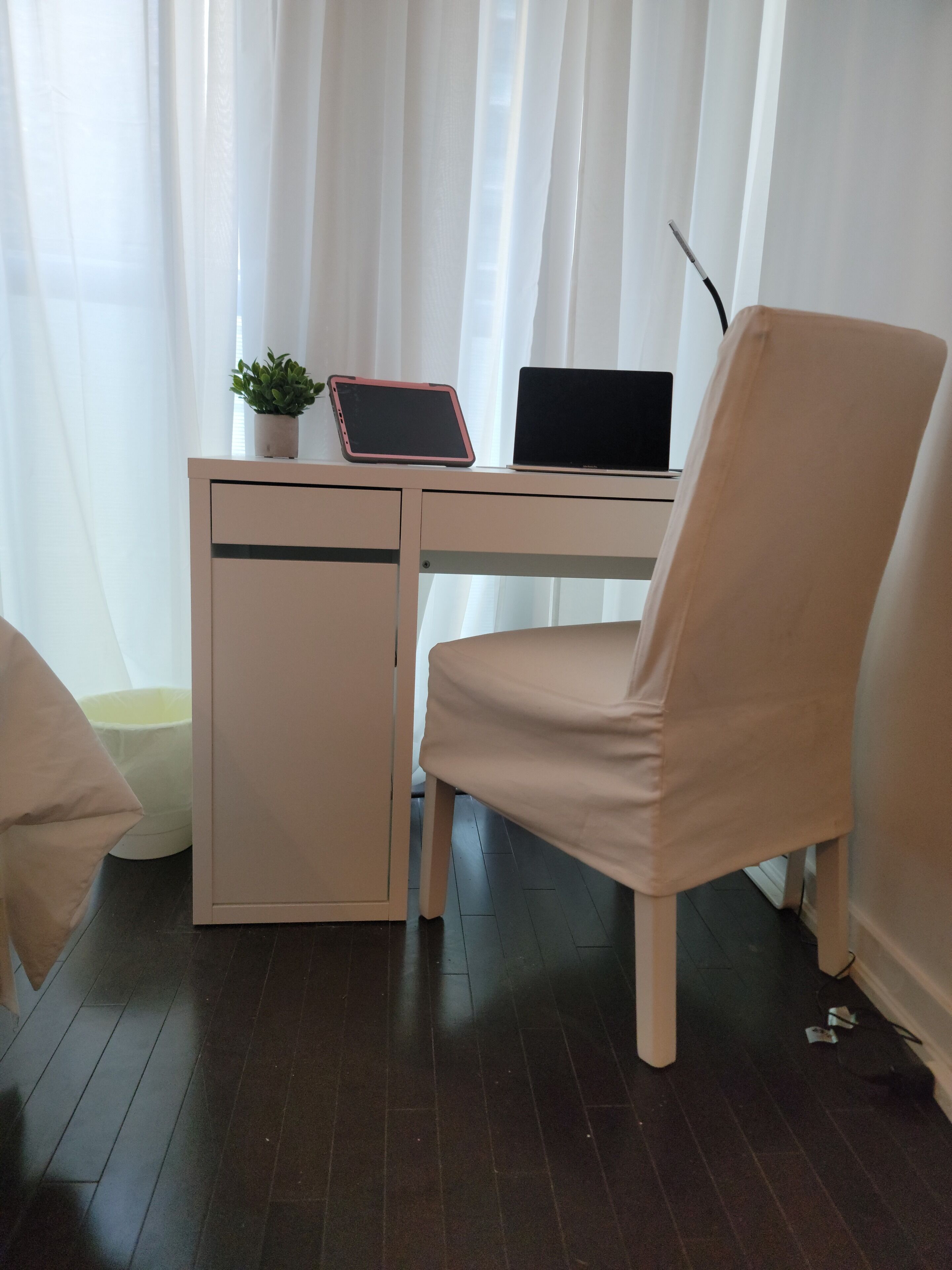 A small, neatly organized workspace with a desk, chair, and two electronic devices.