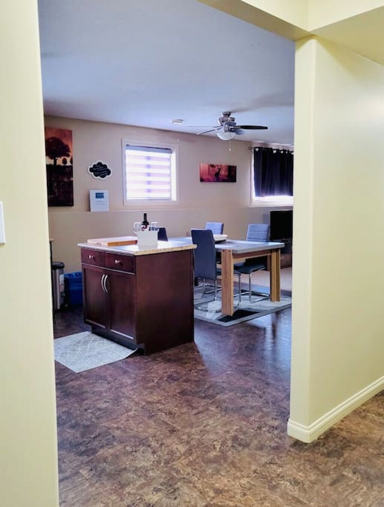 A kitchen with a central island, a dining area with a table and chairs, and a ceiling fan.