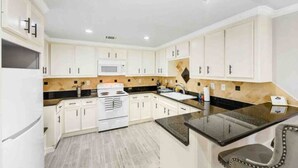 Una cocina moderna con armarios blancos, encimera negra y pileta de acero inoxidable.