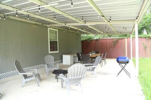 Un patio couvert avec une table et des chaises, un barbecue et une fenêtre.