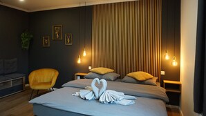 Una habitación de hotel moderna con una cama, dos mesitas de noche, un sillón amarillo y una pared con listones de madera verticales.