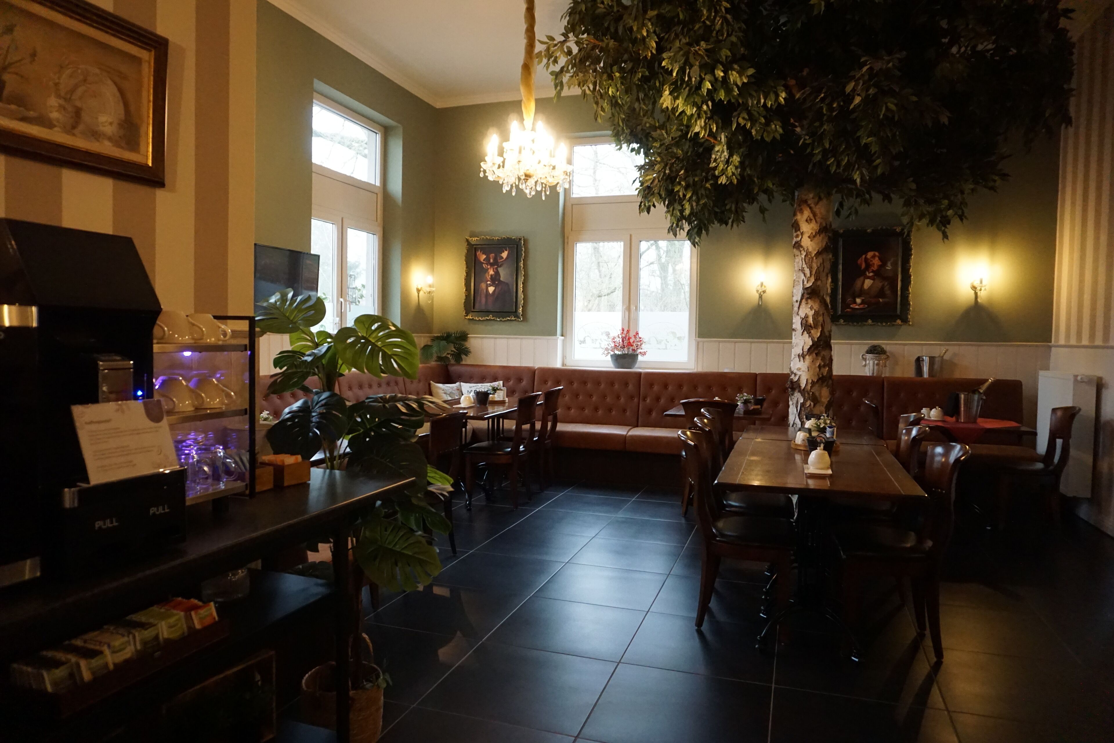 Un restaurante con una amplia mesa de comedor, asientos acolchados y una araña.
