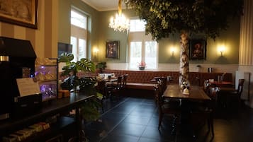 Un restaurante con una amplia mesa de comedor, asientos acolchados y una araña.