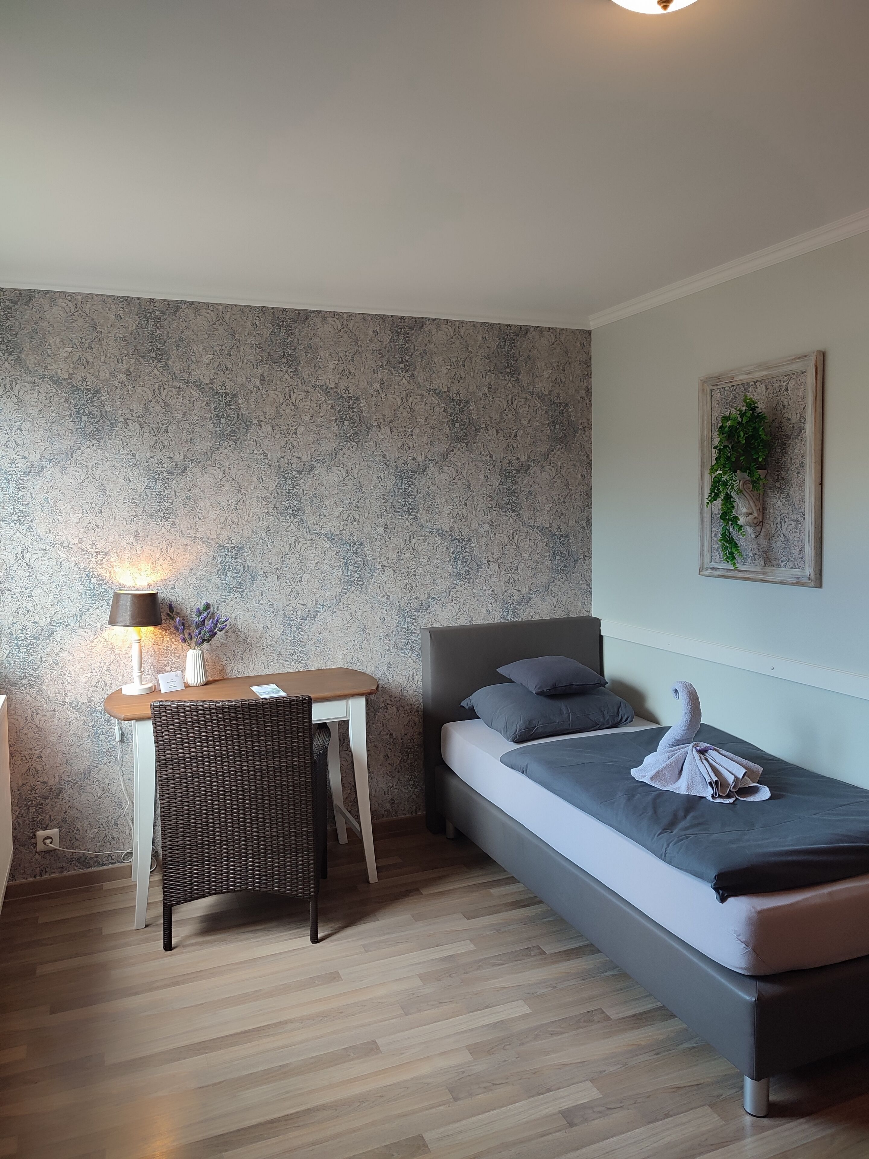 Een kleine, moderne kamer met een bed, bureau en stoel.
