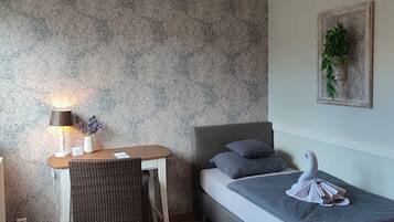 Een kleine, moderne kamer met een bed, bureau en stoel.