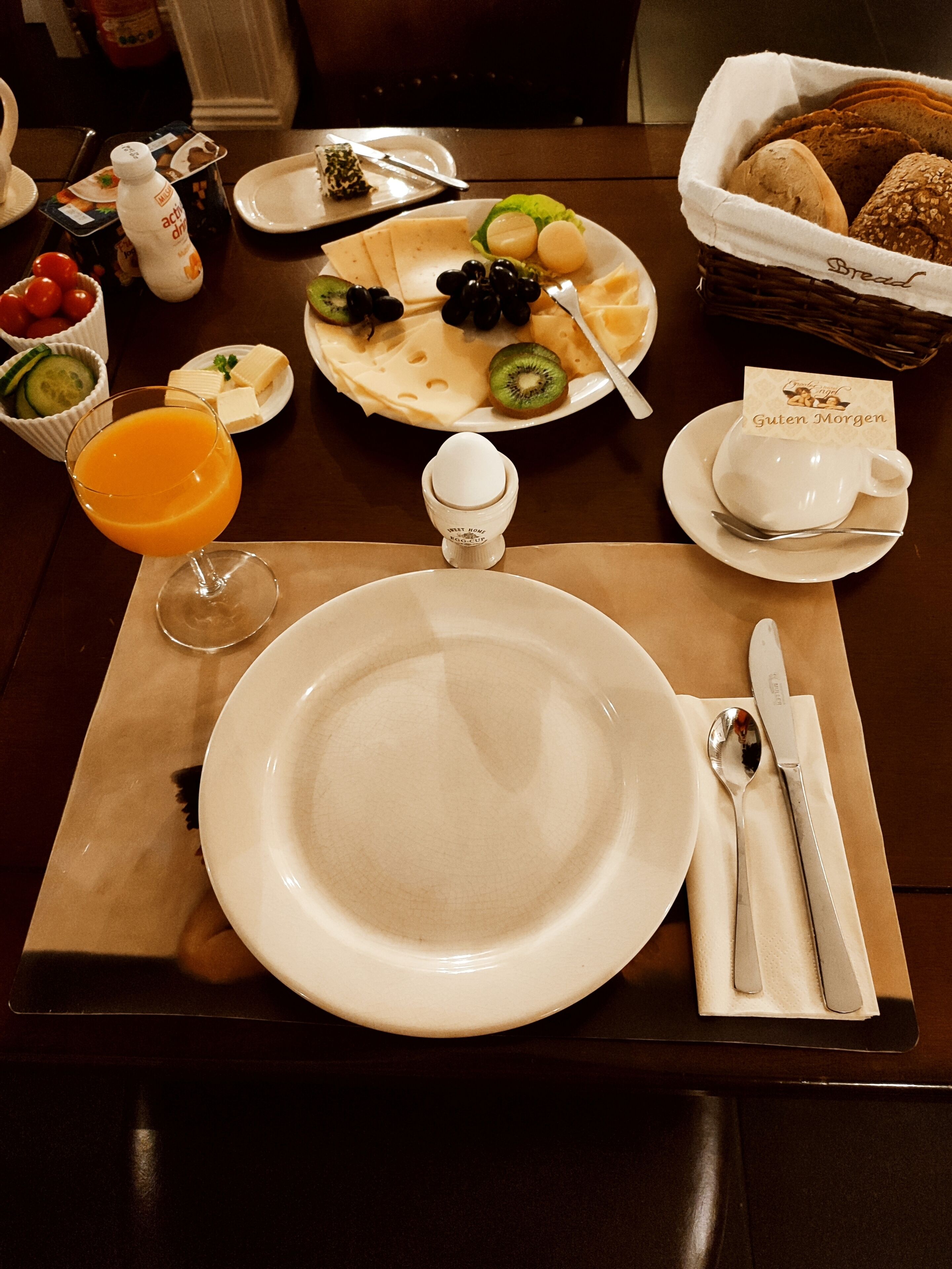 A breakfast setting with a plate of cheese, fruits, and a glass of orange juice.