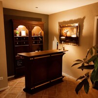 A room with a wooden cabinet, a framed picture on the wall, and a potted plant.