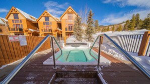 A hot tub area with wooden steps leading up to it, surrounded by a wooden fence and snow-covered ground. - Antlers Gulch 403 (Keystone)