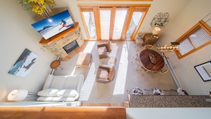 A spacious living area with a stone fireplace, multiple seating options, and a large TV on the wall. - Antlers Gulch 403 (Keystone)