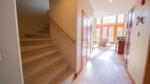 A staircase leading to a second floor, a hallway with a door, and a kitchen area with cabinets and a countertop. - Antlers Gulch 403 (Keystone)
