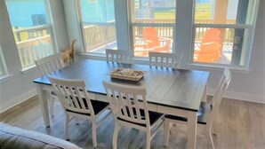 Zona pranzo con tavolo e sedie, ampie finestre e vista su posti a sedere all'aperto.