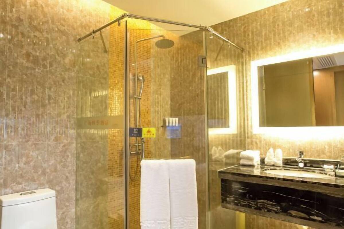 Ein modernes Badezimmer mit einer Glasdusche, einem Marmorwaschbecken und einem großen Spiegel.