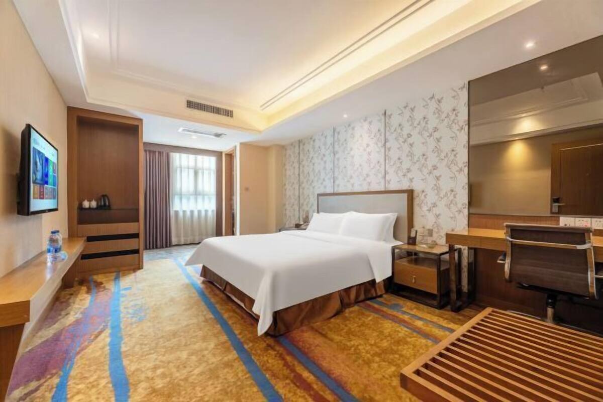 Ein Hotelzimmer mit Bett, Schreibtisch, Stuhl und Fernseher.