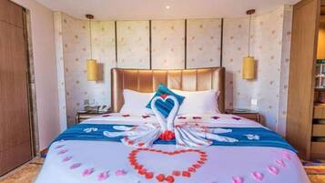 A hotel room with a large bed, a headboard, two bedside lamps, and a nightstand.