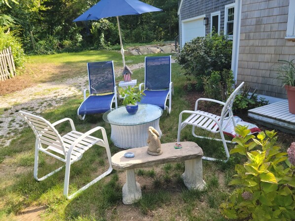 Relax in a serene garden setting with an outdoor seating area featuring a round table and four chairs.