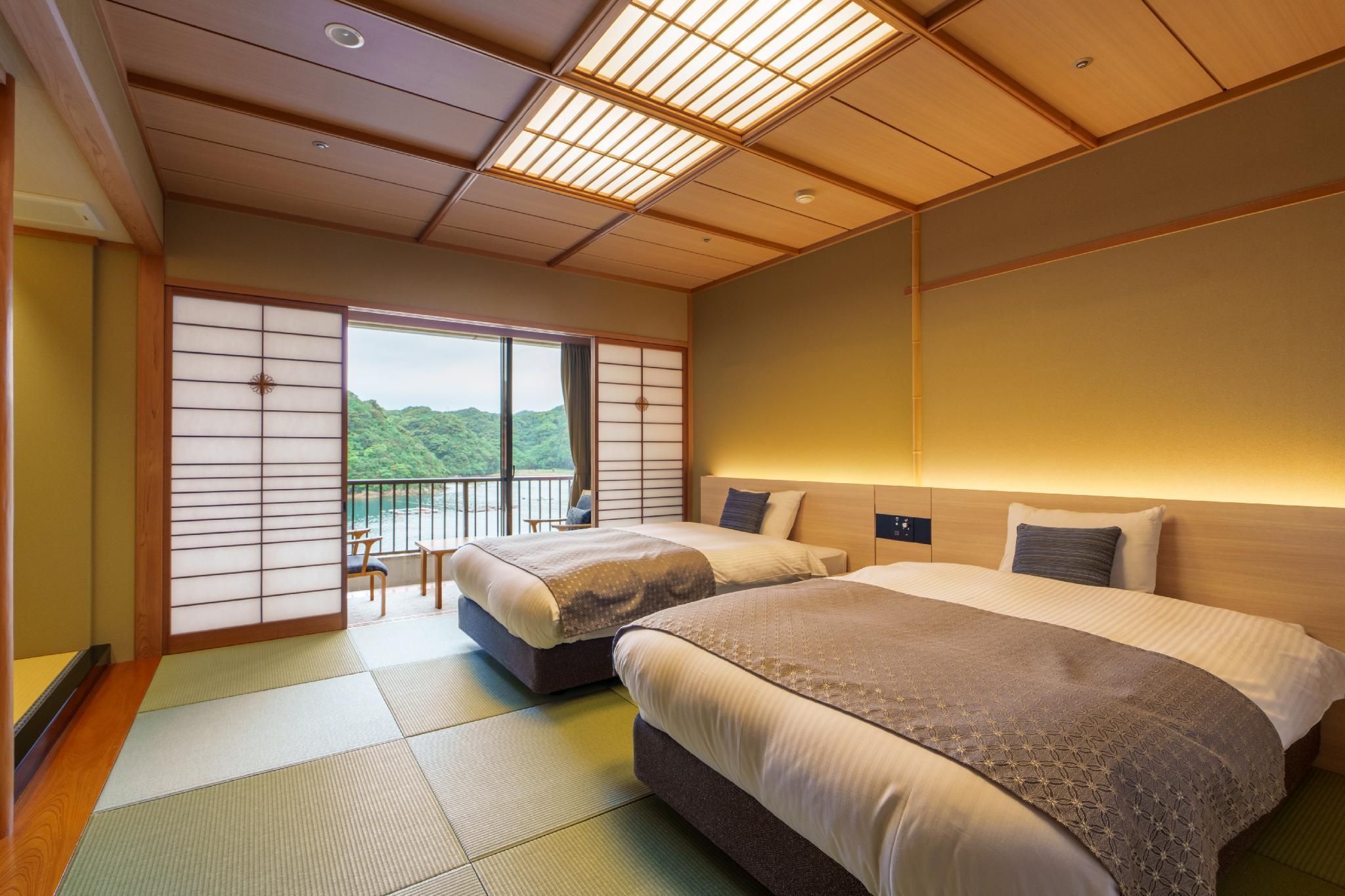 A hotel room with two beds, tatami flooring, a sliding shoji screen, and a view of greenery.