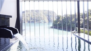 Una fuente de agua con cascada, un balcón con vistas a un cuerpo de agua y colinas.