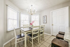 A dining area with a table and chairs, a chandelier, and a framed word on the wall.