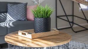 A round wooden table with a woven tray and a potted plant.