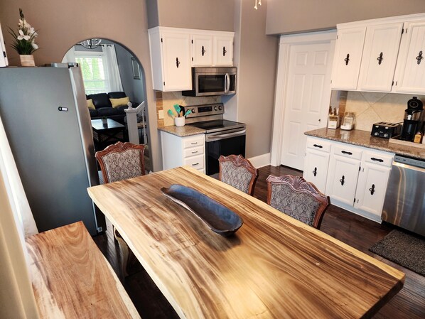 Una cocina moderna con armarios blancos, una mesa de comedor de madera y un horno empotrado.