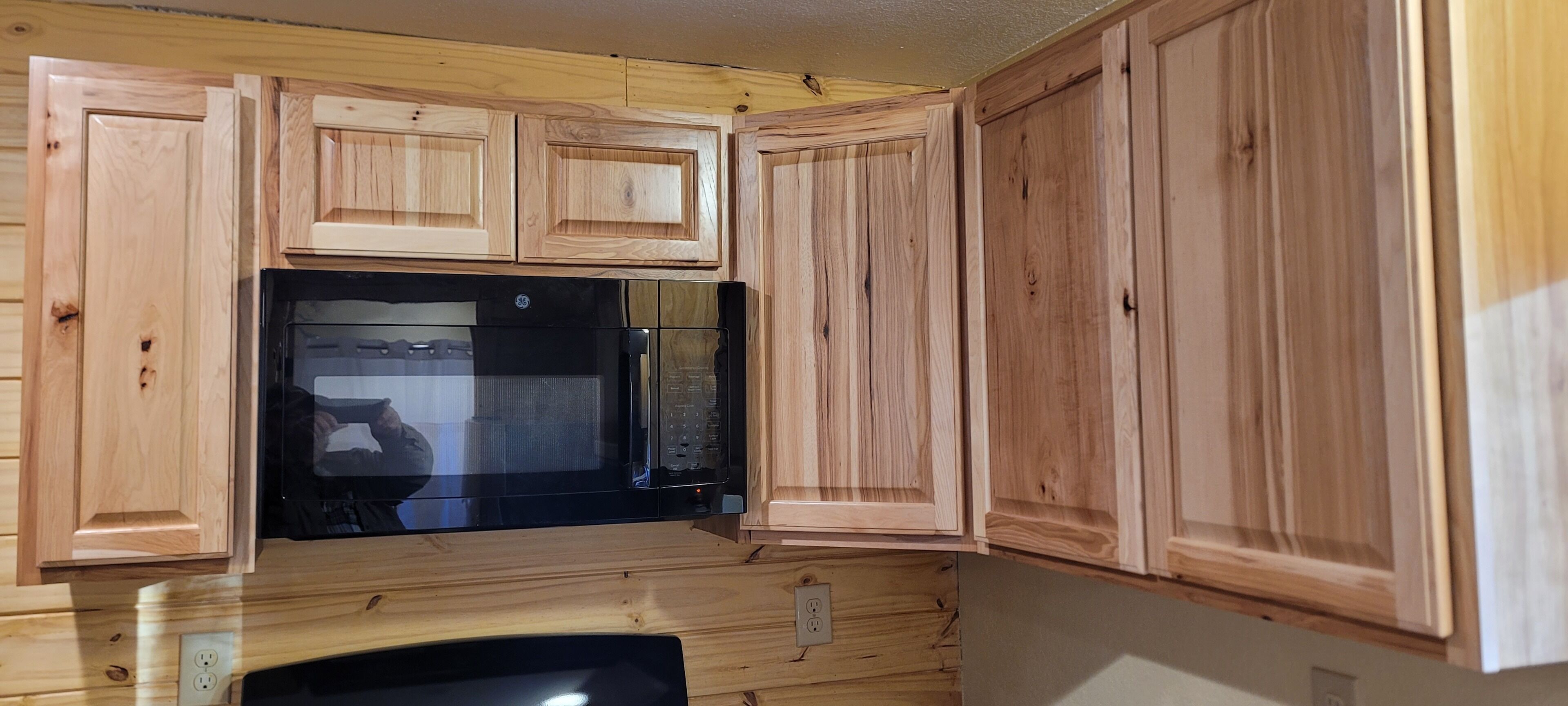 A kitchen with wooden cabinets and a black microwave.