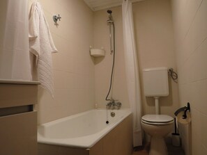 Bathroom features a bathtub, toilet, and showerhead.