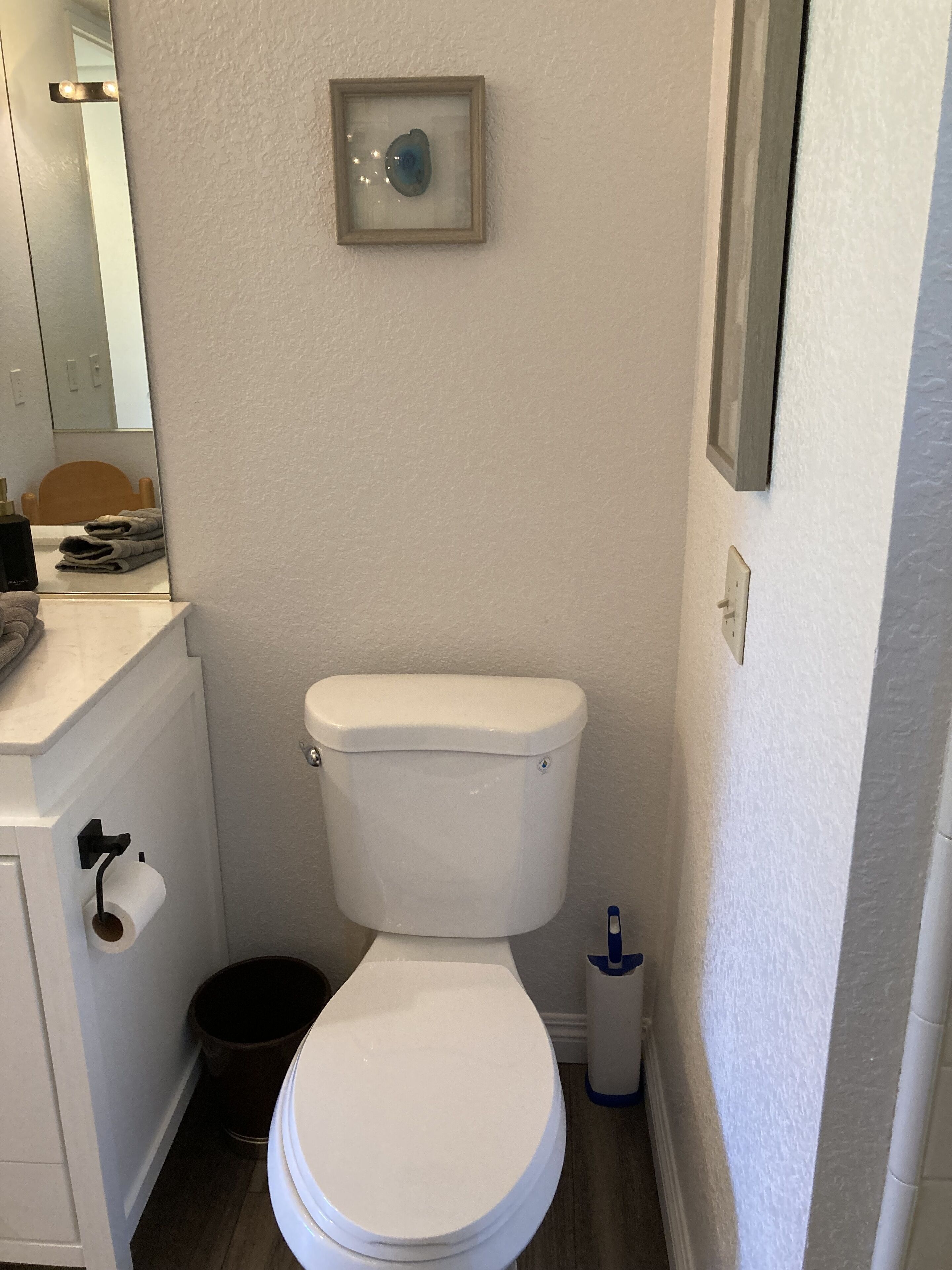 A small, clean bathroom with a toilet, a sink, and a mirror.