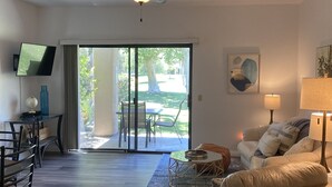 Ett rymligt vardagsrum med en takfläkt, en soffa, ett soffbord och en tv som är monterad på väggen.