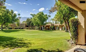 A courtyard with a well-maintained lawn, several trees, and a building with a beige exterior.
