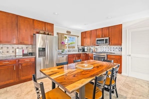 A modern kitchen with wooden cabinets, stainless steel appliances, and a central island with seating.