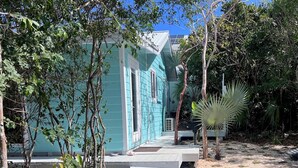 A pathway leading to a turquoise building surrounded by trees and plants. - The Surf Cottage - Beach and Jungle all in One!  An off the grid cottage. (Gregory Town)