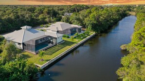 Una casa moderna con una amplia fachada de vidrio, piscina y un río al fondo.