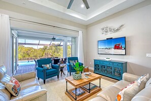 A spacious living room with a large window, a television, and a pool view. - Waterfront Key West Style Home with Heated Pool Located in South Gulf Cove (Port Charlotte)