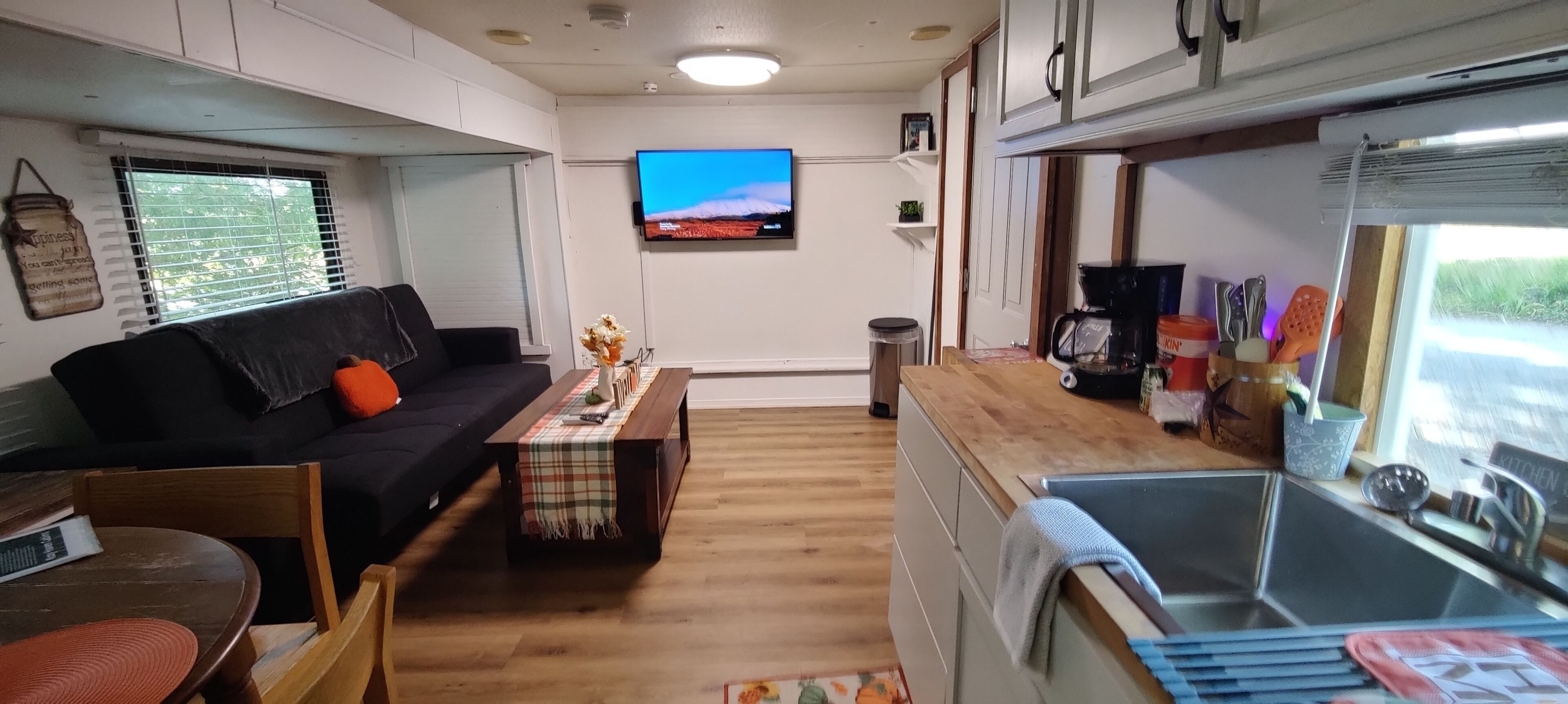 Un espacio habitable compacto con sofá, mesa de centro, televisor y kitchenette.