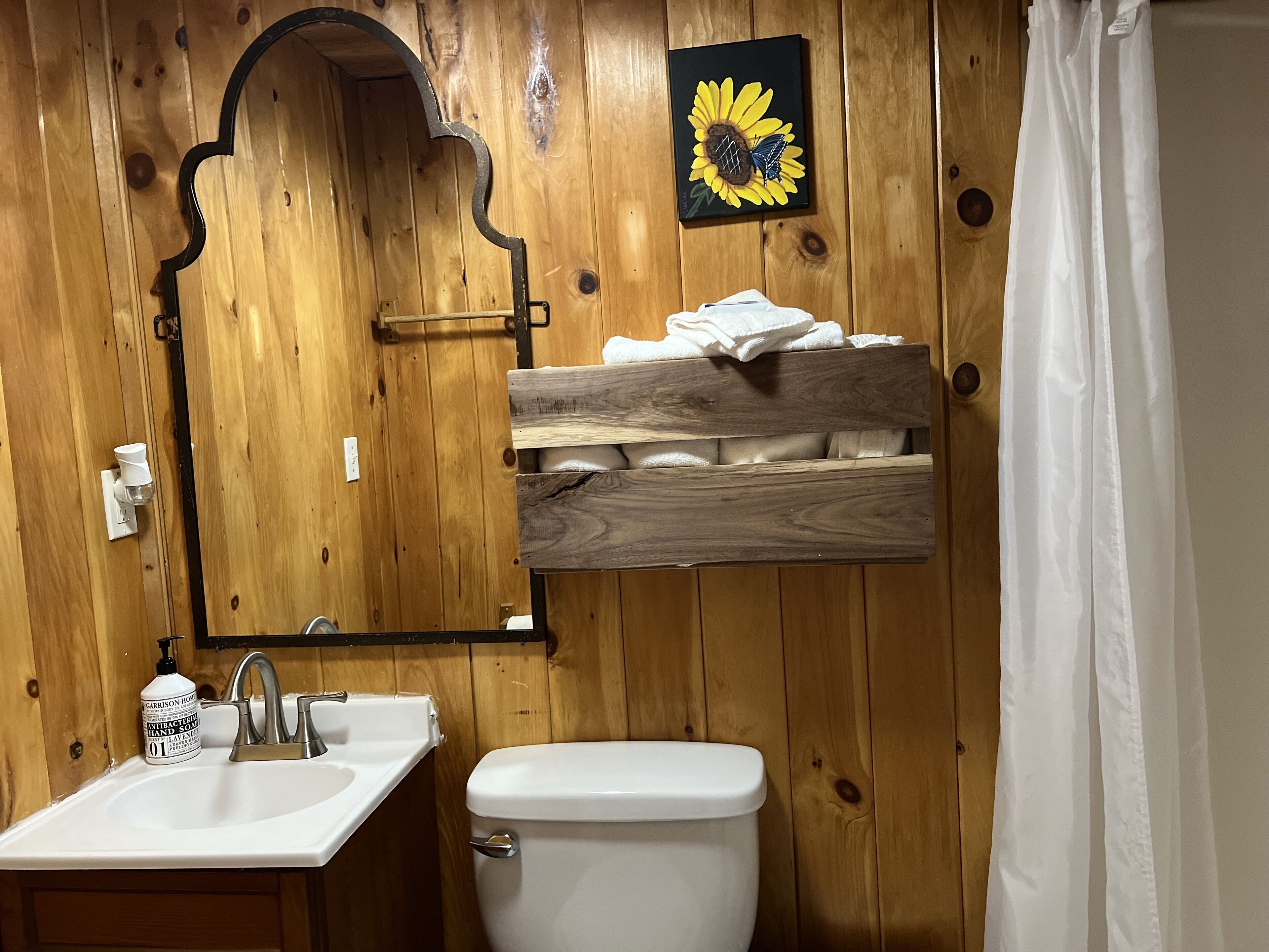A wooden bathroom with a sink, toilet, and a mirror.