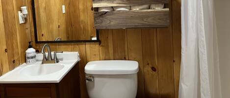 A wooden bathroom with a sink, toilet, and a mirror.